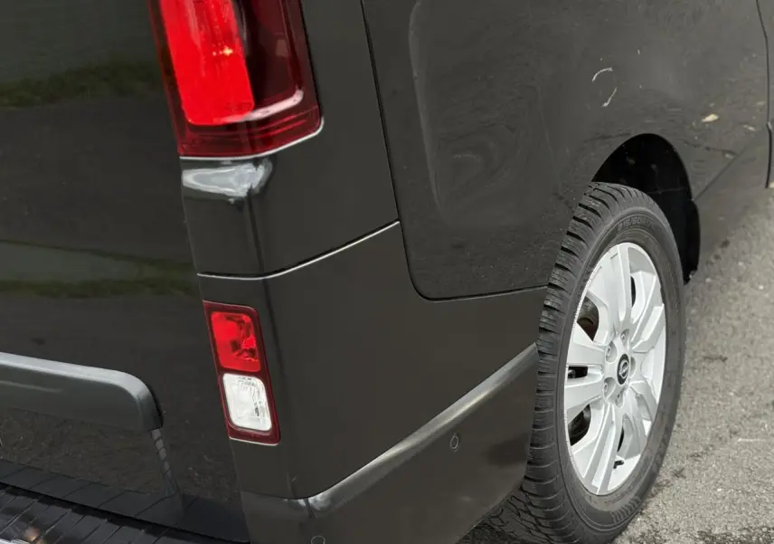 Gros plan sur l'arrière droit noir métallisé du Nissan Primastar Combi avec feu arrière et jante alliage 17 pouces.