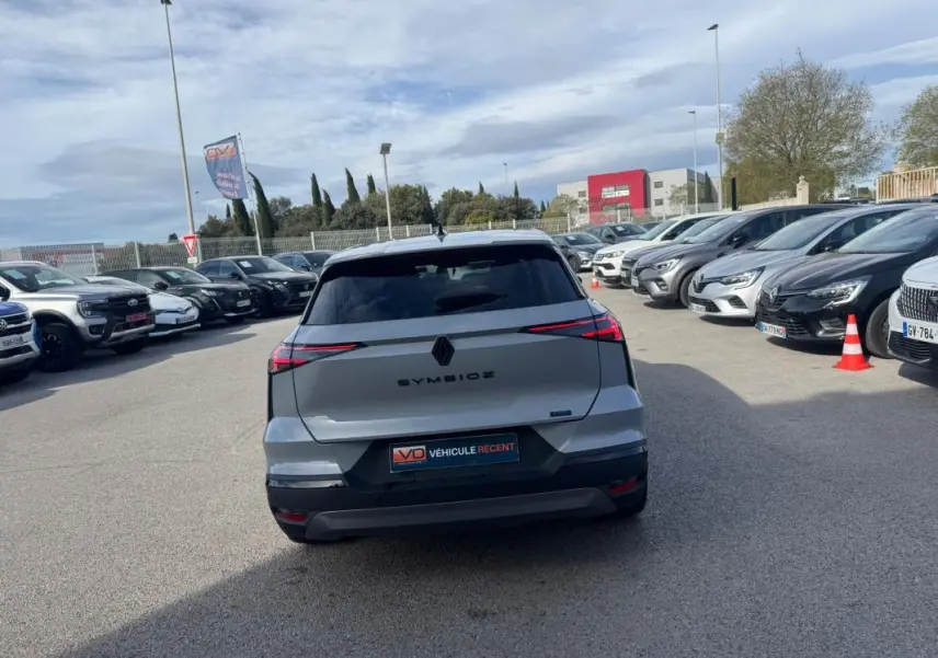 Vue arrière d'une Renault SYMBIOZ gris clair 2025 avec feux LED fins et antenne requin sur parking.