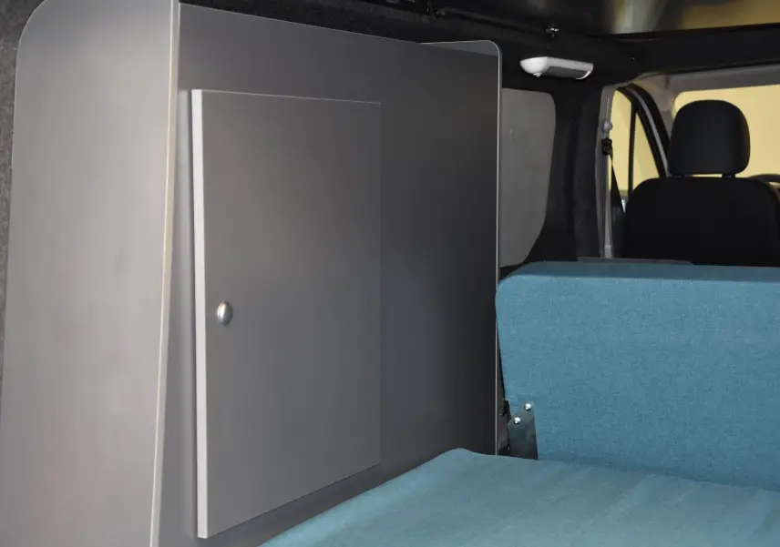 Intérieur du Renault Trafic Combi 2021 montrant un meuble gris et une banquette bleue côté droit, avec sièges avant noirs.