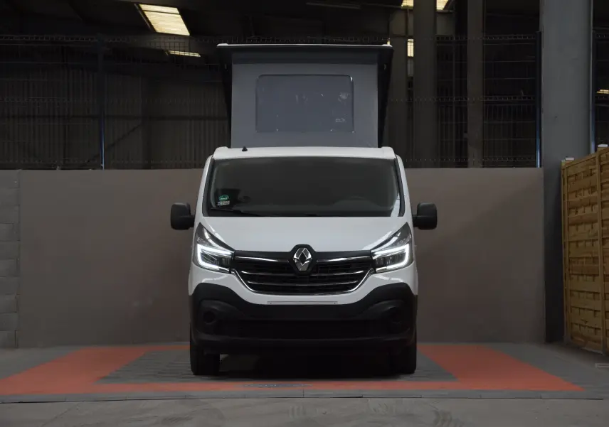 Vue frontale d'un Renault Trafic Combi blanc 2021 avec toit relevé et phares LED allumés dans un garage.