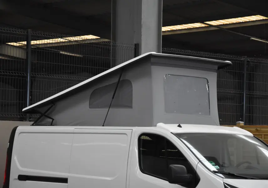 Vue de profil droit d'un Renault Trafic Combi blanc 2021 avec toit relevable gris en position ouverte.