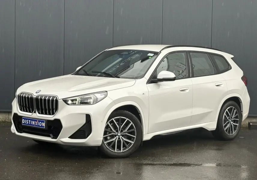 BMW X1 sDrive 20d blanc Mineral vue 3/4 avant droit avec calandre imposante et jantes bicolores 18 pouces.