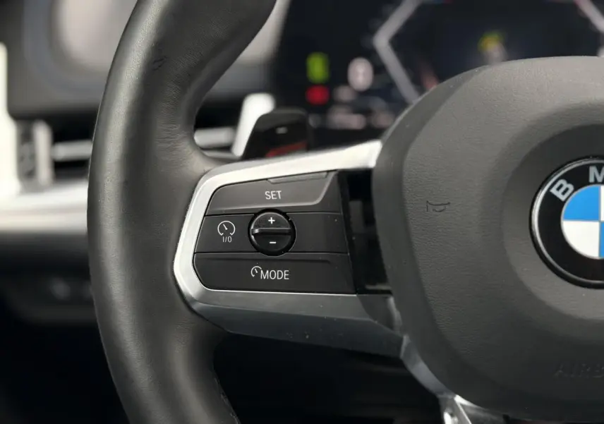 Gros plan sur le côté gauche du volant cuir M de la BMW X1 blanc Mineral avec commandes multifonctions.