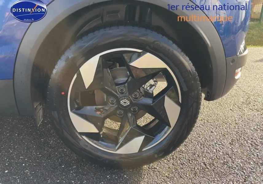 Gros plan sur la roue avant droite du Renault Captur bleu iron avec jante alu bicolore au design moderne.