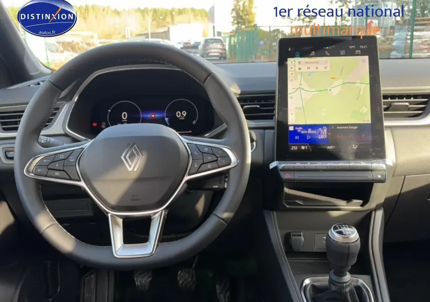 Vue intérieure avant du tableau de bord du Renault Captur bleu iron 2025 avec volant multifonction et écran tactile vertical.