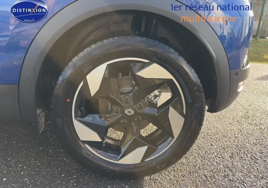 Gros plan sur la roue avant droite d’un Renault Captur Bleu Iron avec jante alu au design géométrique.