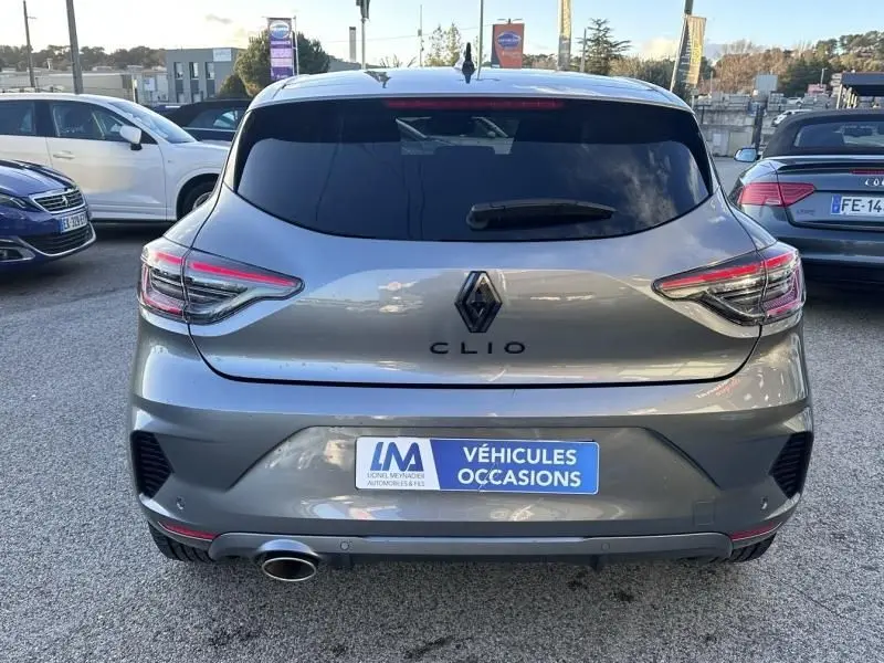 Vue arrière d’une Renault Clio V gris shiste 2025 avec feux LED et sortie d’échappement visible, en extérieur sur parking.