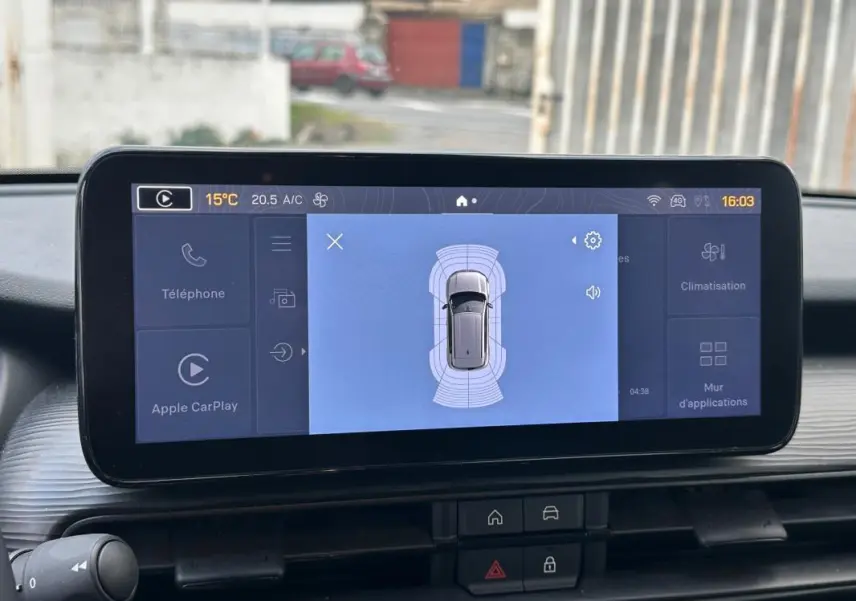 Vue rapprochée de l'écran central du Jeep Avenger noir 2025 affichant l'aide au stationnement et les options connectées.