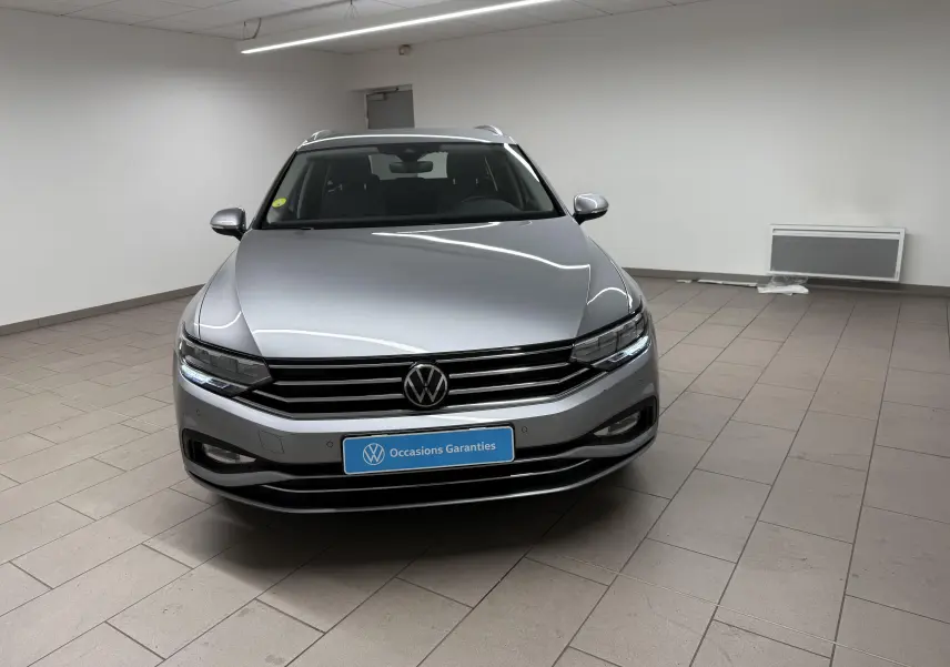 Volkswagen Passat SW 2.0 TDI 122 DSG7 Business gris pyrite vue de face en intérieur, avec calandre et phares LED allumés.