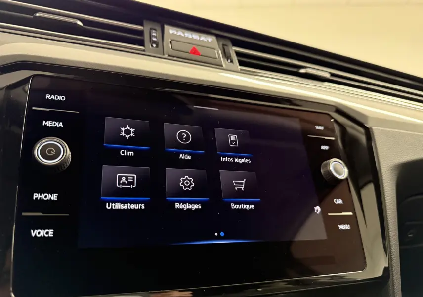 Vue rapprochée de l’écran tactile central de la Volkswagen Passat SW 2024 avec menu des réglages et finition noire brillante.