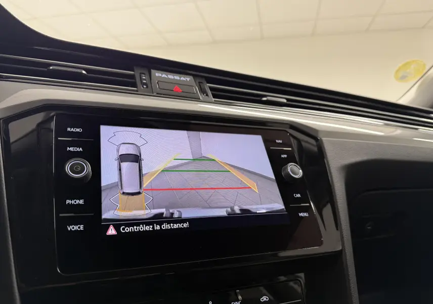 Vue rapprochée de l'écran tactile intérieur de la Volkswagen Passat SW gris pyrite montrant l'aide au stationnement arrière.