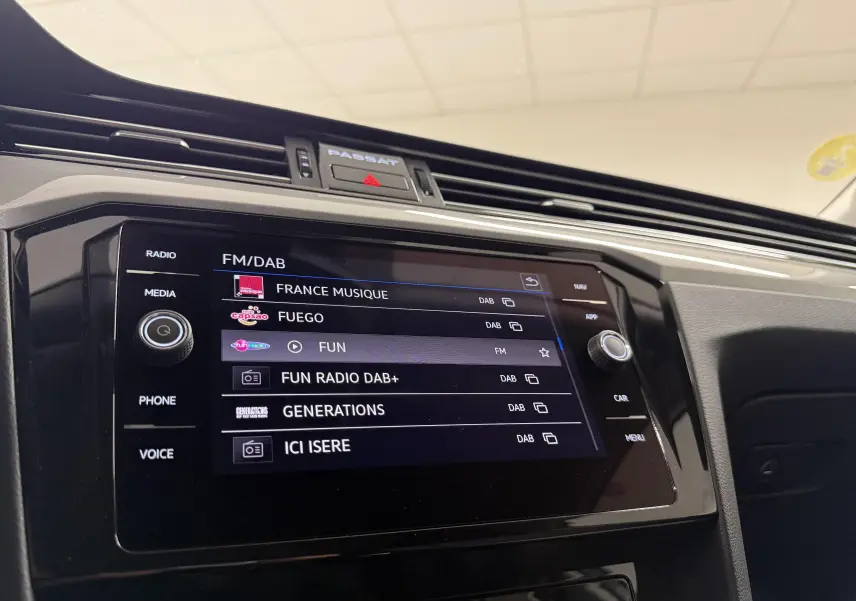 Vue rapprochée de l’écran multimédia de la Volkswagen Passat SW 2024, affichant les stations radio FM/DAB.