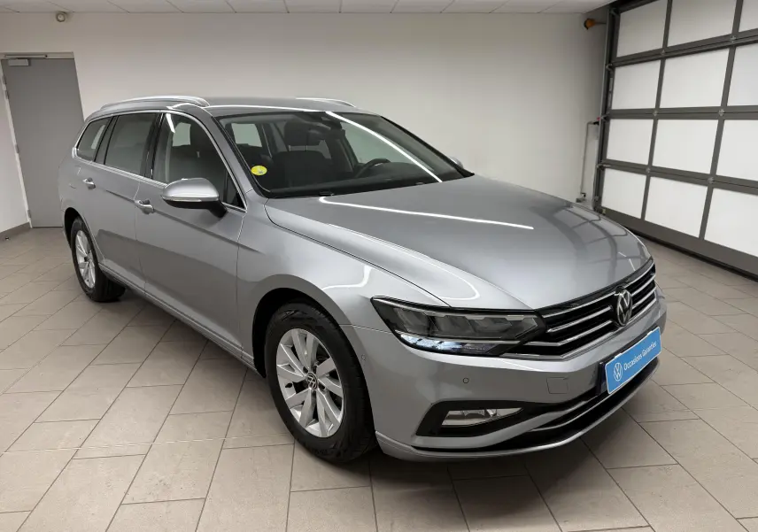 Vue 3/4 avant droite d'une Volkswagen Passat SW 2024 gris pyrite avec calandre chromée et phares LED distinctifs.
