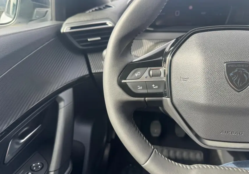 Vue rapprochée du volant et de la portière côté gauche du Peugeot 2008 2024, intérieur noir avec finitions texturées.