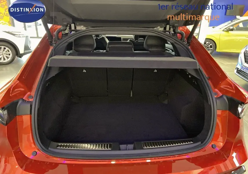 Coffre ouvert vu de l'arrière d'une Renault Rafale 2024 rouge flamme métal, intérieur noir et banquette rabattue.