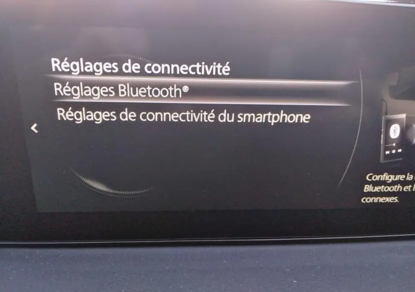 Écran central du tableau de bord du Mazda MX-30 gris 2021 montrant les réglages de connectivité Bluetooth.