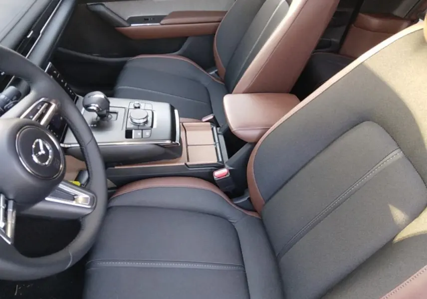 Vue intérieure rapprochée du Mazda MX-30 2021 gris, montrant sièges bi-matière noirs et marron avec console centrale moderne.