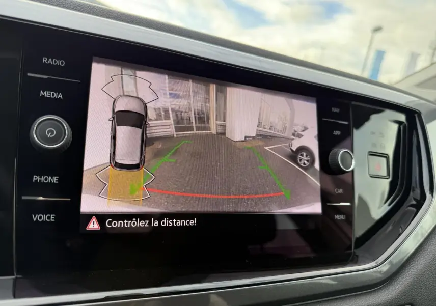 Écran tactile intérieur montrant la caméra de recul active d'une Volkswagen Polo argent métallisé en stationnement.