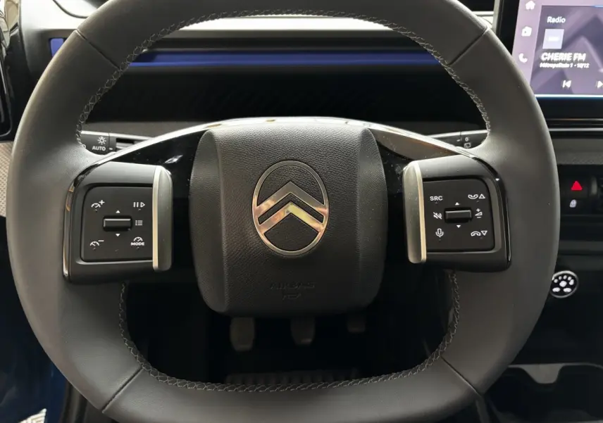 Gros plan sur le volant cuir noir de la Citroën C3 100 BVM PLUS 2025 avec commandes multifonctions et écran tactile visible.