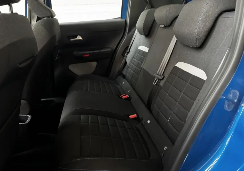 Vue intérieure côté droit sur la banquette arrière noire de la Citroën C3 100 BVM PLUS bleu 2025 avec appuie-têtes intégrés.