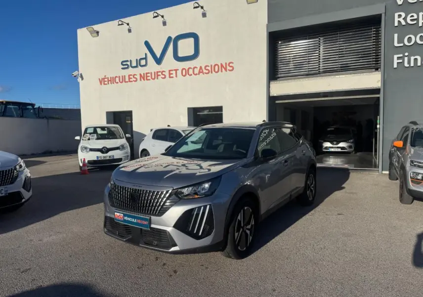 Peugeot 2008 Hybrid gris en 3/4 avant droit, avec barres de toit et jantes alliage 17 pouces visibles.