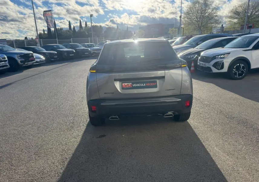 Vue arrière d’un Peugeot 2008 Hybrid gris 2024 avec feux LED fins et double sortie d’échappement visible en concession.