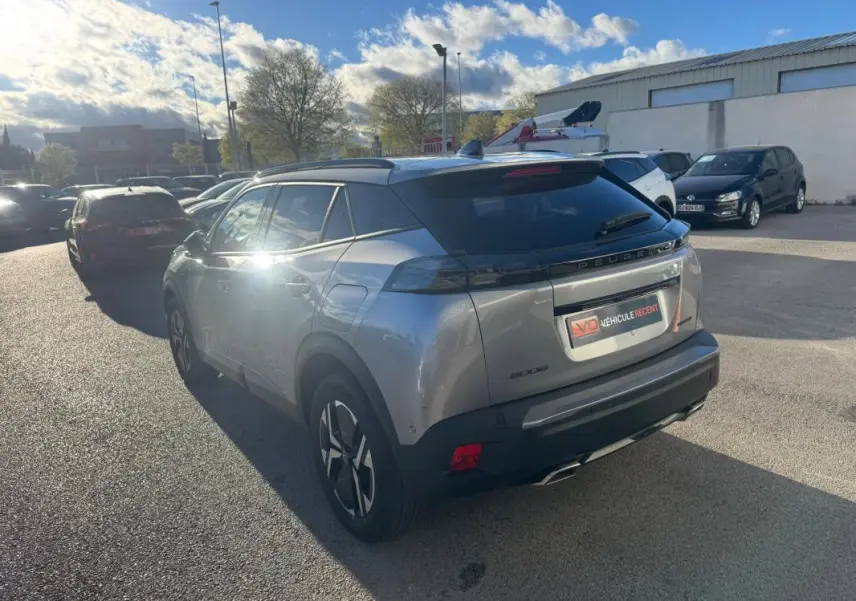 Peugeot 2008 Hybrid gris en 3/4 arrière droit, avec barres de toit et jantes alliage 17 pouces visibles.
