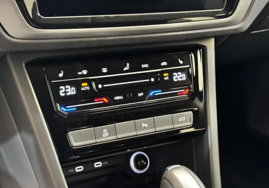Gros plan sur la console centrale du Volkswagen Touran 2024, avec commandes climatisation digitale et levier de boîte automatique.