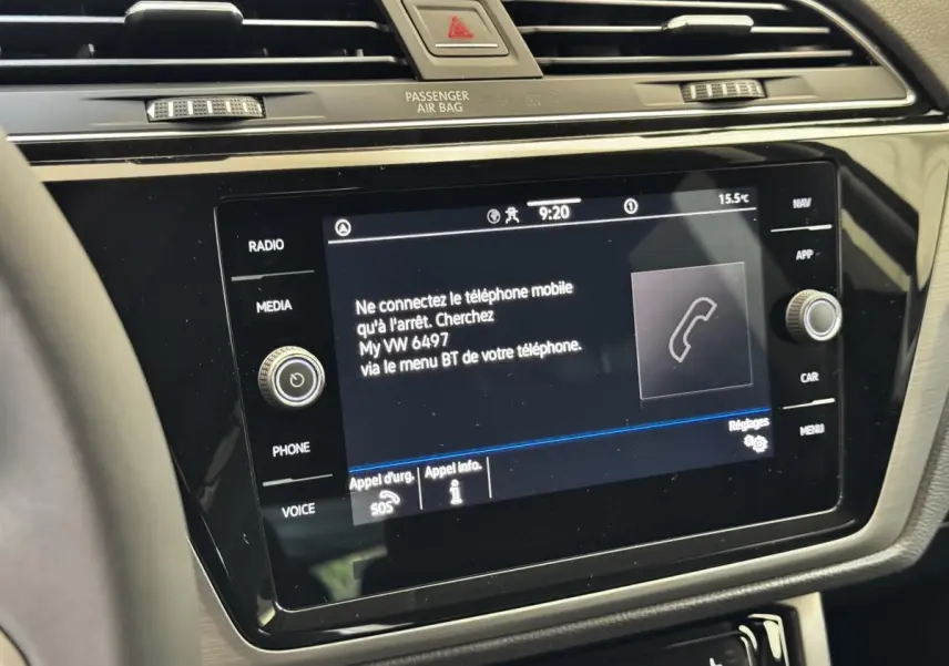 Vue rapprochée de l’écran tactile central noir du tableau de bord du Volkswagen Touran 2024, affichant un message d’appairage téléphone.