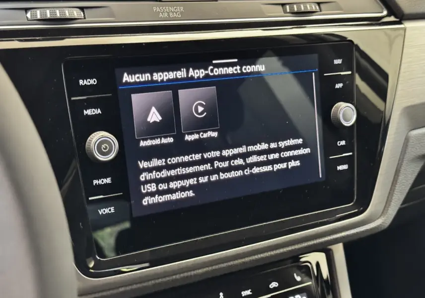 Vue rapprochée de l’écran tactile central et des commandes noires du tableau de bord intérieur du Volkswagen Touran 2024.