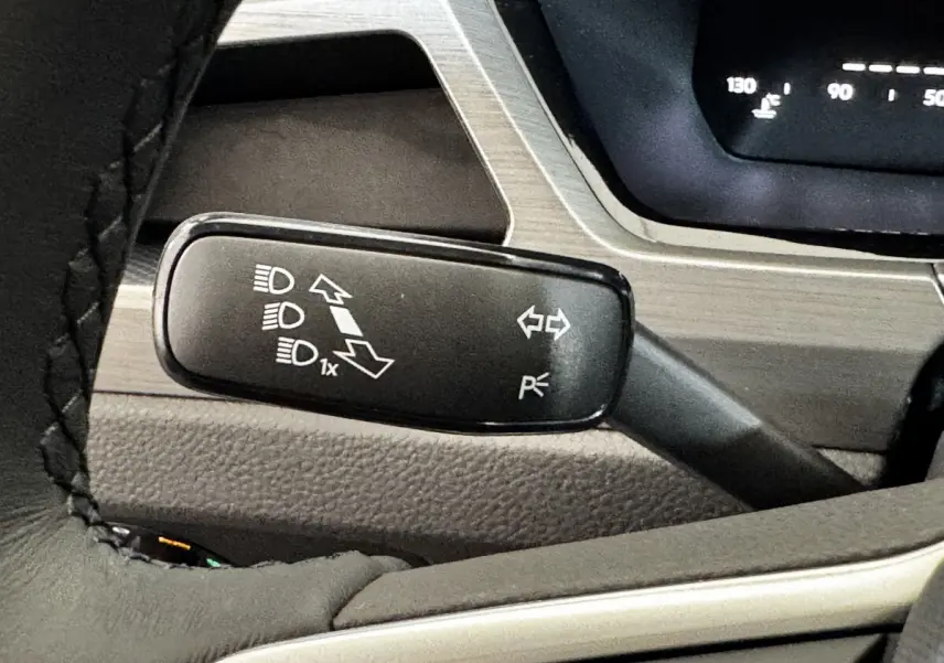 Gros plan sur la manette de commande des phares et clignotants du Volkswagen Touran 2024, intérieur gris.