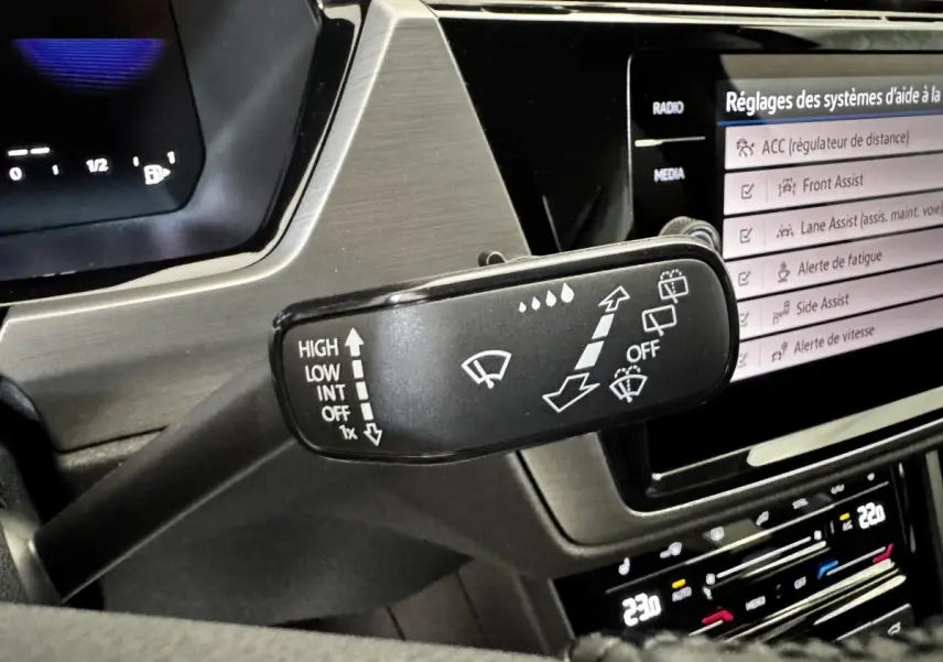 Gros plan sur la commande des essuie-glaces du Volkswagen Touran 2024, avec écran tactile et tableau de bord digital.