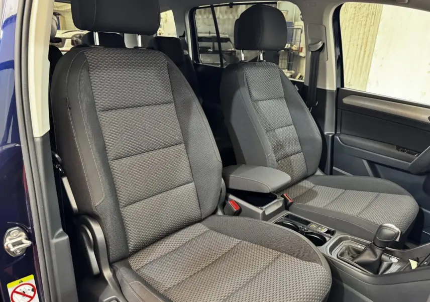 Vue intérieure côté avant droit du Volkswagen Touran 2024 bleu, sièges tissu gris avec console centrale et levier de vitesse.