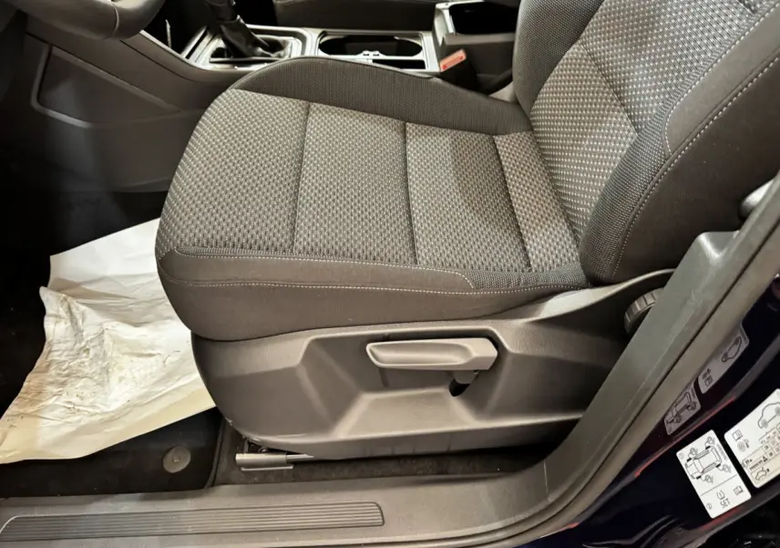Vue rapprochée du siège avant droit gris foncé du Volkswagen Touran 2024, avec réglage manuel et porte ouverte bleu.