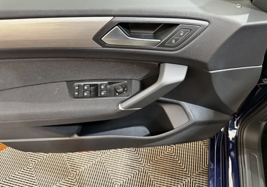 Vue intérieure côté conducteur de la porte avant bleu foncé du Volkswagen Touran 2024 avec commandes de vitres et verrouillage.