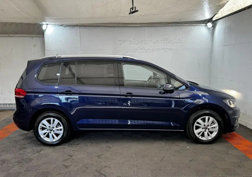 Vue latérale droite d'un Volkswagen Touran bleu 2024, montrant ses lignes épurées et ses jantes alliage.