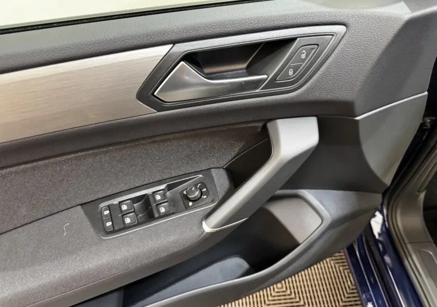 Vue intérieure côté conducteur de la porte d’un Volkswagen Touran bleu avec commandes de vitres et verrouillage.