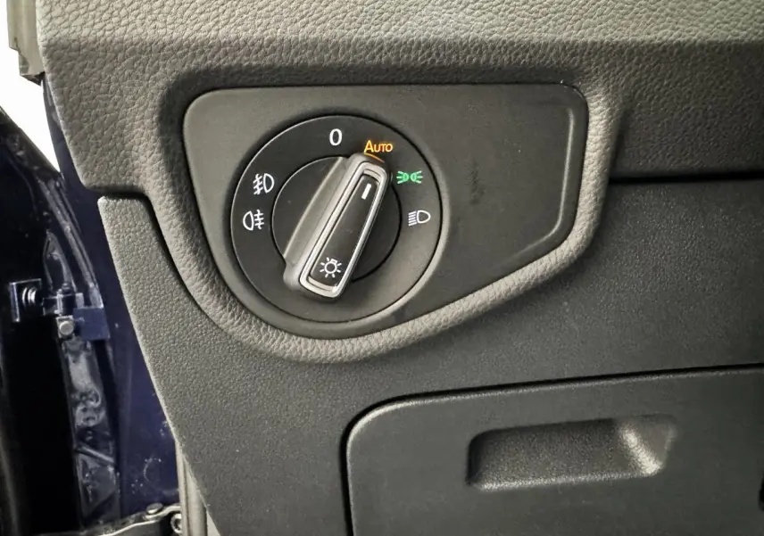 Gros plan sur le bouton de commande des phares dans l’habitacle du Volkswagen Touran bleu, côté conducteur.