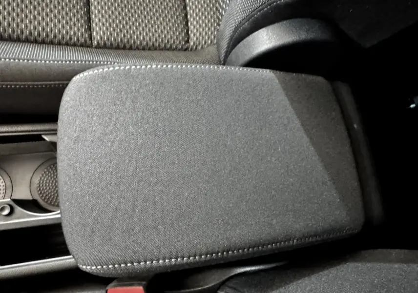 Détail de l'accoudoir central noir en tissu dans l'habitacle du Volkswagen Touran 2024, côté conducteur.
