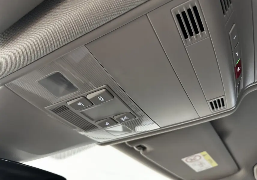 Vue en plongée sur le plafonnier gris avec commandes d’éclairage et ventilation du Volkswagen Touran 2024 bleu.