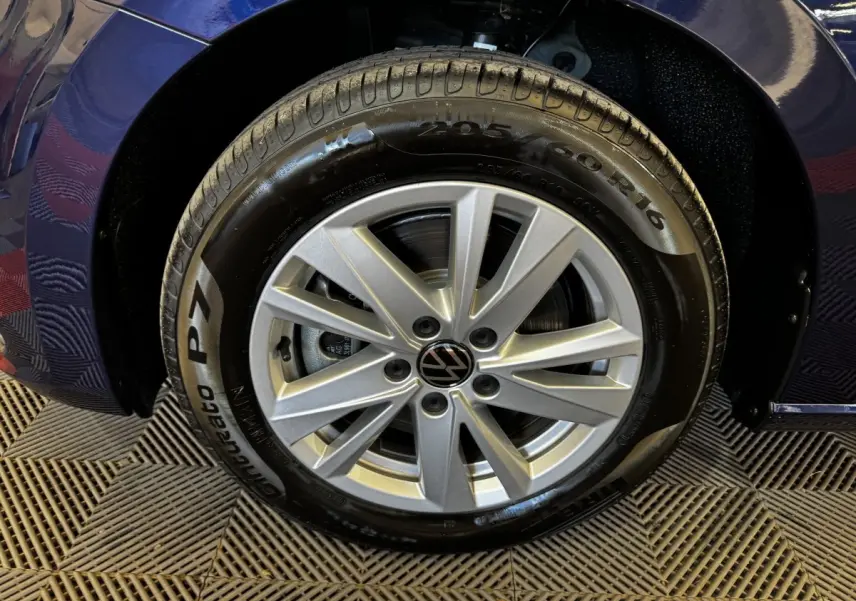 Gros plan sur la roue avant droite du Volkswagen Touran bleu 2024 avec jante alliage argentée et pneu Pirelli.