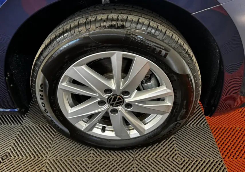 Gros plan sur la roue avant droite d’un Volkswagen Touran bleu 2024 avec jante alliage argentée et pneu Pirelli.