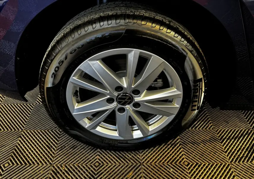 Gros plan sur la roue avant droite d’un Volkswagen Touran bleu 2024 avec jante alliage et pneu Pirelli.