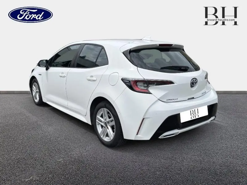 Vue 3/4 arrière droite d'une Toyota Corolla blanche Pure avec feux arrière LED et double sortie d'échappement chromée.