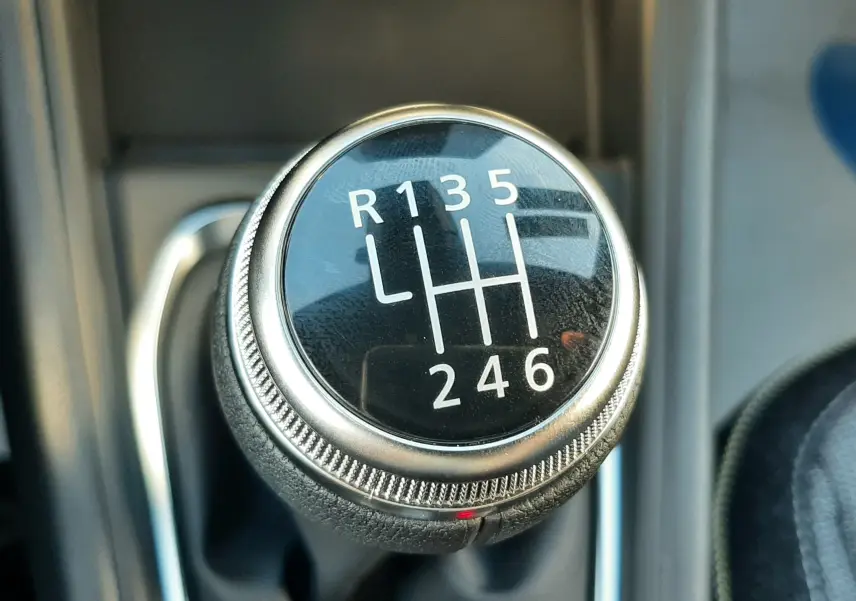 Gros plan sur le levier de vitesses manuel du Renault Captur bleu Iron, montrant les six rapports et la marche arrière.