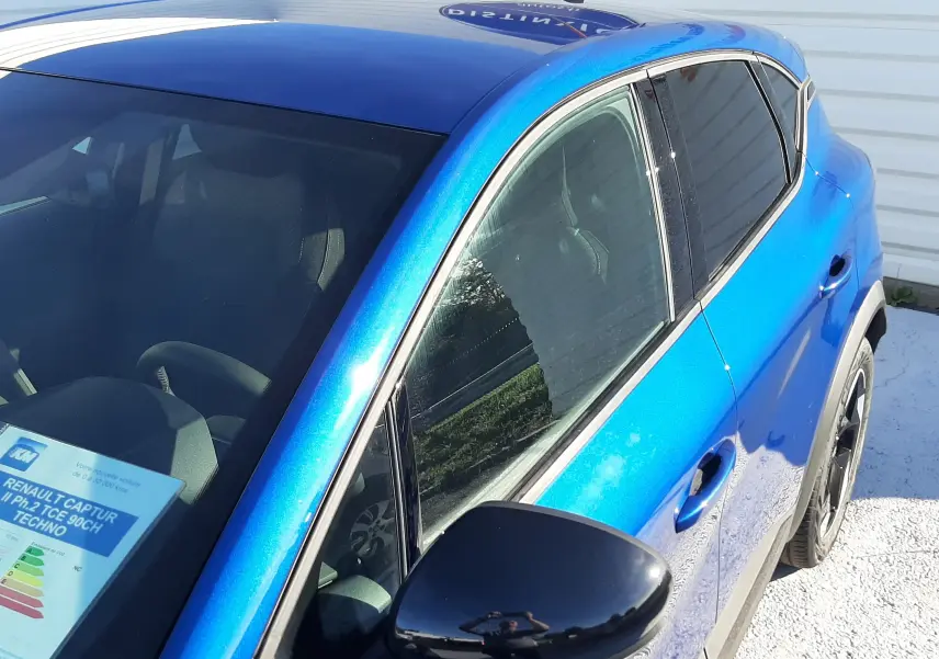 Vue de trois quarts avant droit du Renault Captur II Ph.2 TCE 90CH TECHNO bleu Iron avec rétroviseur noir brillant.