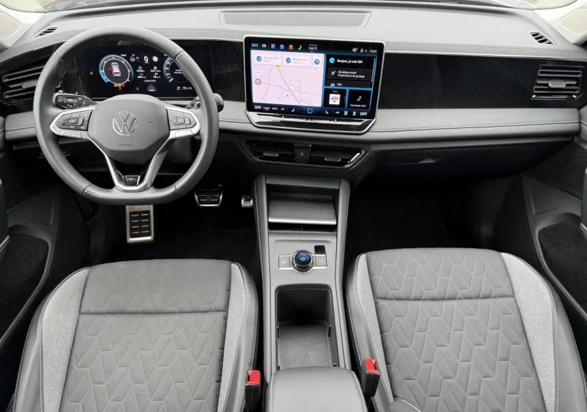 Vue intérieure frontale du Volkswagen Tiguan 2025, tableau de bord moderne avec écran tactile et sièges gris à motifs géométriques.