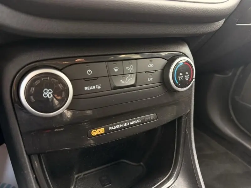 Vue rapprochée de la console centrale noire du Ford Puma 2026, avec commandes de climatisation et témoin airbag passager.