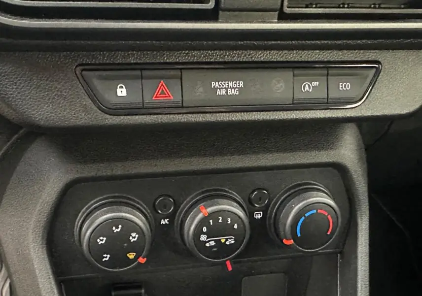 Gros plan sur la console centrale noire du Dacia Sandero 2024, montrant les commandes de climatisation manuelle.