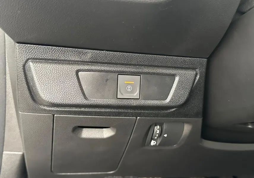 Gros plan sur le tableau de bord noir de la Dacia Sandero 2024, montrant le bouton de fermeture centralisée et réglages lumineux.